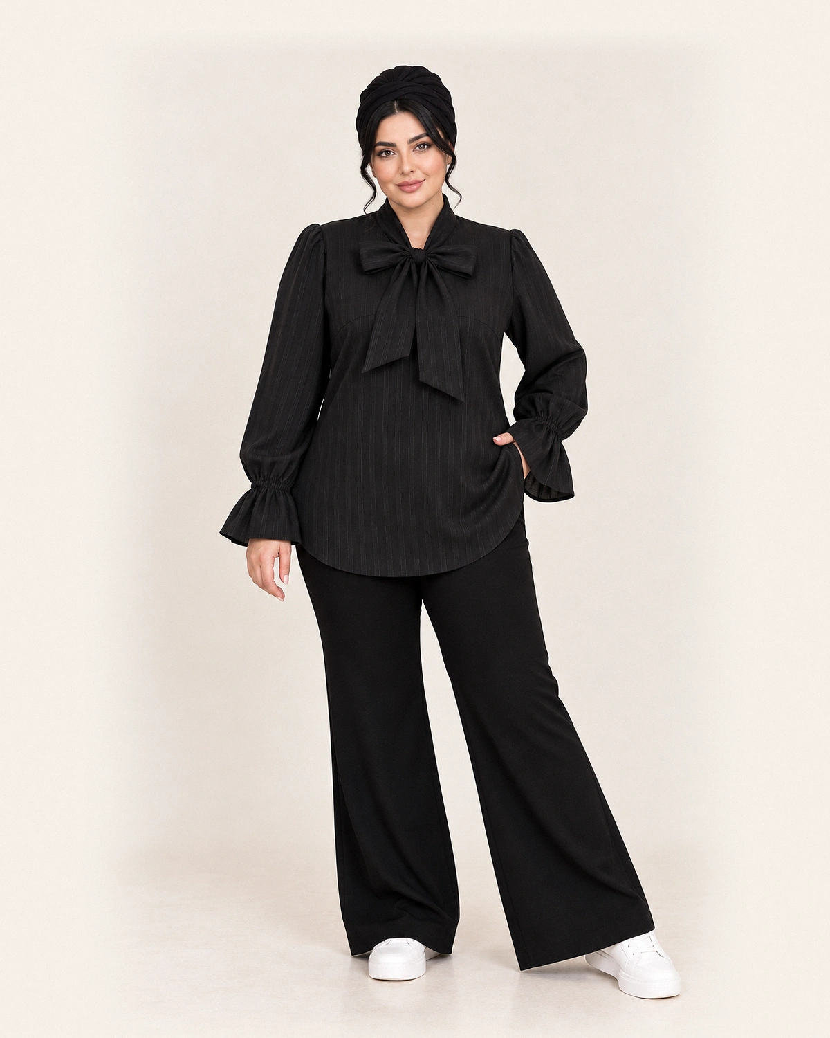 splus-2327-black-tie-neck-blouse-front.webp شومیز مشکی یقه پاپیونی کد ۲۳۲۷ با خطوط راهراه عمودی و آستین کلوش روی مدل
